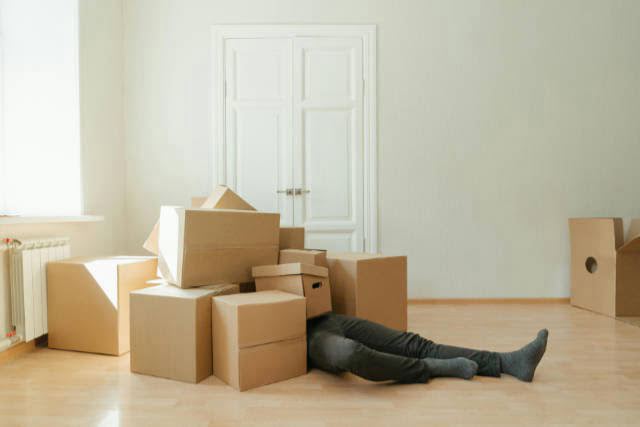 Man buried in moving boxes in a room